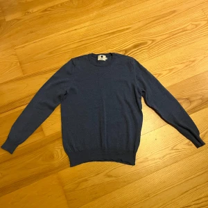 Blå tröja från NN07 - Säljer en stilren blå tröja från NN07. Tröjan har en klassisk rund hals och långa ärmar, perfekt för kyligare dagar. Den är tillverkad i ett mjukt material som ger en bekväm passform. Passar utmärkt till både jeans och chinos.