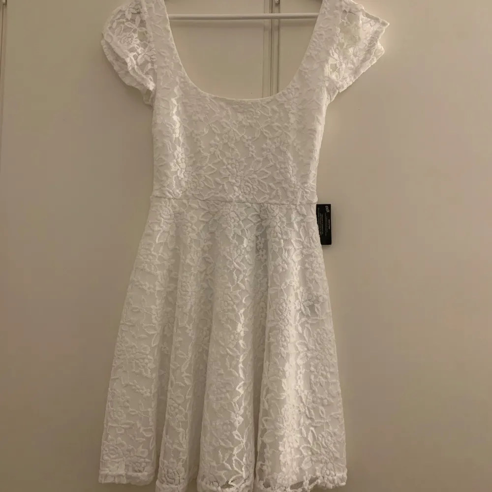 Charmig vit spetsklänning med kort ärm och rundad hals. Klänningen har en figurnära passform upptill och en utsvängd kjol som ger en fin silhuett. Perfekt för sommarens festligheter, till student eller konfirmation💕. Mekot.
