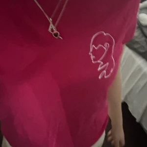 Rosa t-shirt med tryck - Snygg rosa t-shirt med ett stilrent vitt tryck av en ansiktssiluett på bröstet. Kortärmad och i en härlig rosa färg. Skriv vid intresse!!!💕💕💕