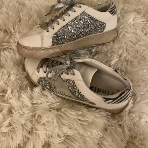 unika glittriga sneakers🫶🏻 - säljer dessa jättecoola sneakers som har en stjärndetalj på sidan och zebramönster på hälen<3 det ingår glittriga snören men man kan även byta till vita för en lite mer stilren look!💓nypris är 800