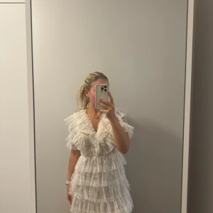 Vit spetsklänning med volanger - Säljer en superfin vit klänning i spets med volanger från by malina. Den har en v-ringad design och korta ärmar. Endast använd en gång så är som i nyskick!💕
