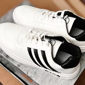 Nya herrskor i storlek 43 med 2st bälten 130 cm - Vita sneakers med svarta ränder.   Nya och eleganta herrsko - tillgängliga i storlek 43 med matchande 2st bälten 130 cm  Upptäck stil och komfort med våra nya herrskor, designade för att passa alla smaker. Kompletteras med två eleganta bälten som mat