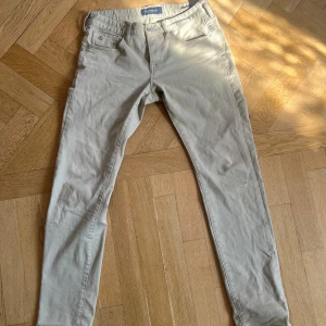 Beige byxor från Scotch & Soda - Säljer ett par snygga beige byxor från Scotch & Soda. De är i en slim passform och har en klassisk design med fickor både fram och bak. Perfekta för både vardag och lite mer uppklädda tillfällen. Byxorna är i bomull och har en bekväm midwaist.