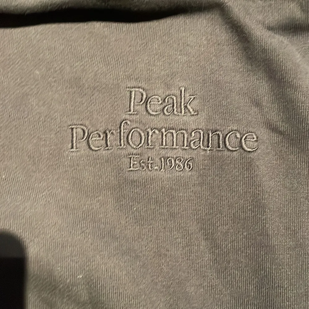 Säljer en snygg och bekväm grå hoodie från Peak Performance. Den har en klassisk design med en känguruficka framtill och en broderad logga på bröstet. Perfekt för både vardag och chill dagar. Passar bra till höst och vinter!. Hoodies.