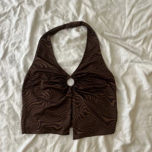 Brunt linne - Ett brunt linne med mönster och en öppning mellan brösten.