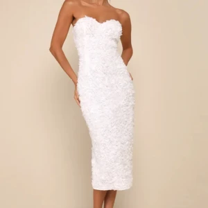 Vit axelbandslös klänning - Perfekt studentklänning🤍🤍Säljer en superfin vit axelbandslös klänning med en tight passform. Klänningen har textur med små blommiga detaljer över hela tyget. Skriv för fler bilder. Aldrig använd!!!