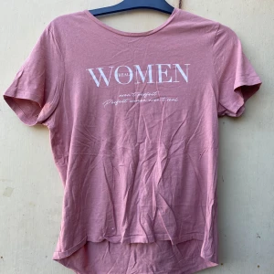 Rosa t-shirt från Amisu - Säljer en snygg rosa t-shirt från Amisu med texten 'Real Women' tryckt på framsidan. Den är kortärmad och gjord i ett mjukt bomullsmaterial, perfekt för vardagsbruk. T-shirten har en avslappnad passform och är i bra skick. Perfekt för sommardagar eller som en del av en lager-på-lager-look.