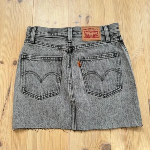 Grå jeanskjol från Levi's - Säljer en grå jeanskjol från Levi's. Den har en rå avklippta kant nertill. Fint skick!