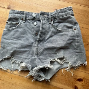 Grå jeansshorts från Zara - Säljer ett par grå jeansshorts från Zara i storlek XS. De har en cool, sliten look med fransiga kanter, midrise. Perfekta för sommaren och festivaler! 🕶️