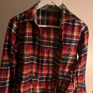 Ruitig skjorta från UNIQLO - Sparsamt använd rödrutig skjorta från Uniqlo. Storlek 152cm/12år. Skriv privat för fler bilder!