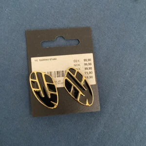 Svarta och guldiga örhängen från Glitter - Säljer ett par snygga svarta och guldiga örhängen från Glitter. De har en cool, modern design med ett geometriskt mönster. Perfekta för att piffa upp vilken outfit som helst!