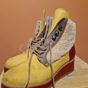 Färgglada boots med pälsdetaljer - Säljer ett par unika boots i gult, rött och beige med pälsdetaljer. De har snörning och en rejäl platåsula som ger extra höjd. Perfekta för höst och vinter när du vill sticka ut lite extra. Skorna är i bra skick och redo för nya äventyr!