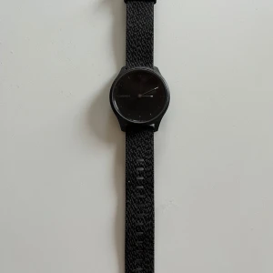 Garmin Vivomove Style smartwatch - Smartwatch från Garmin, modell Vivomove style, 42 mm. Grafitfärgat aluminiumhölje med svartfärgat vävt nylonarmband. I mycket bra skick, enstaka små ytliga slitage (se bilder), fullt fungerande. Kommer med laddare.   Mer info: https://www.garmin.com/sv-SE/p/662825/pn/010-02240-03