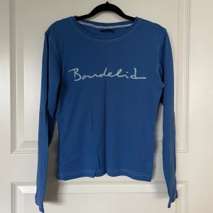 Blå långärmad tröja från Bondelid - Säljer en snygg blå långärmad tröja från Bondelid. Den har en stilren design med Bondelid-loggan tryckt på bröstet. Perfekt för både vardag och avslappnade tillfällen. Tröjan är i bra skick och passar perfekt till jeans eller chinos.