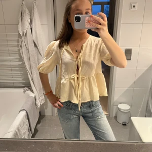 Beige blus med knytband - Säljer en söt ljusgul blus med knytband framtill. 