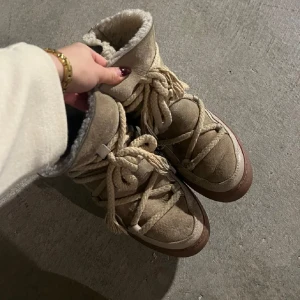 Inuikki - Superfina beige kängor i mycket bra skick, perfekta för vintern! De har en mysig pälsfodring och snygg snörning som ger en cool look. Sulan är robust och ger bra grepp på hala underlag. Perfekta för kalla dagar när du vill hålla dig varm och stilren.