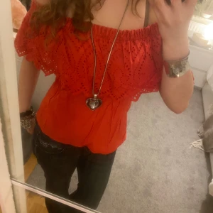Röd offshoulder topp - Säljer en superfin röd offshoulder topp med spetsdetaljer. Perfekt för sommaren och har en jätte söt spets detalj! Den har en elastisk kant upptill för en bekväm passform och är i ett lätt och luftigt material. Passar perfekt till både jeans och kjol. 🥰