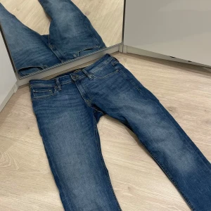 Blå jeans från Jack & Jones Slimfit  - Säljer ett par snygga blå jeans från Jack & Jones i modellen Liam. De har en klassisk femficksdesign och är i bra skick. Perfekta för både vardag och fest! Passar till allt och är superbekväma.  Storlek 31/32