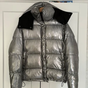 Silver pufferjacka från Bik Bok - Säljer en  silvrig pufferjacka från Bik Bok i storlek S. Perfekt för skidresan🎿. Den har en stor huva och dragkedja framtill. Supervarm och trendig för kalla dagar! ❄️