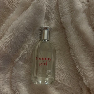 Tommy Girl parfym - Säljer en fräsch och blommig Tommy Girl parfym från Tommy Hilfiger. Flaskan är genomskinlig med röd text och har en stilren silverfärgad kork. Perfekt för dagligt bruk eller speciella tillfällen. Doften är lätt och uppfriskande, idealisk för vår och sommar.