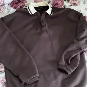 Brun pikétröja med krage - Säljer en stilren brun pikétröja oversize med vit krage och knappar. Tröjan har långa ärmar och är i bra skick. .