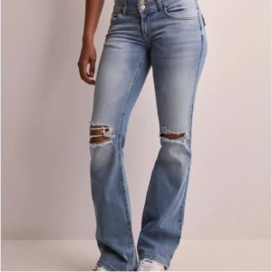 Ljusblå jeans från Nelly  - Säljer ett par snygga ljusblå jeans med slitningar på knäna. De har en låg midia och är helt nya med prislappen kvar 