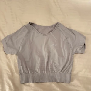 Grå kortärmad crop- topp från ICIW - En snygg grå crop - topp från ICIW i mycket bra skick. Den är kortärmad och har en ribbad nederkant som ger en sportig look. Perfekt för träning eller en avslappnad dag. Använt max 2 gånger. 