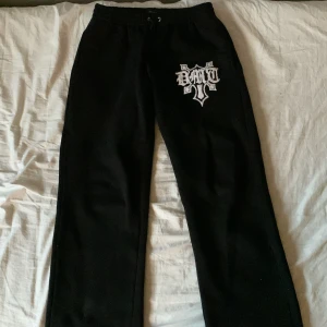 Svarta mjukisbyxor från Demont - Säljer ett par svarta mjukisbyxor från Demont i storlek S. Byxorna har en cool vit logga på ena benet och är perfekta för en avslappnad stil. De har snörning i midjan för bästa passform. Perfekta för chill dagar hemma, en snabb tur till affären eller till en outfit man kan ha på sig i skolan