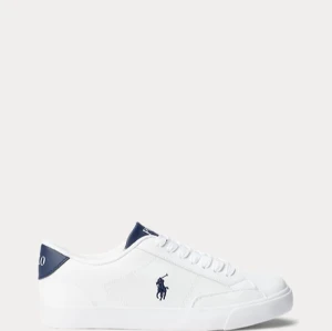 Vita sneakers från Polo Ralph Lauren - Snygga vita sneakers från Polo Ralph Lauren med den klassiska loggan på sidan. Skorna har en stilren design med snörning och en mörkblå detalj vid hälen där märket står skrivet. Perfekta för en casual look!