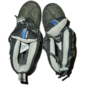 Svarta vinterkängor från Rejka - Säljer ett par robusta svarta vinterkängor från Lejon. De har en slitstark sula och är perfekta för kalla och snöiga dagar. Kängorna har snörning och en praktisk dragflik baktill för enkel påtagning. Insidan är fodrad för extra värme och komfort.