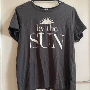 T-shirt med tryck - En grå t-shirt med vit tryck där det står ”by the sun”