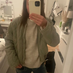 Grön quiltad bomberjacka - Säljer en snygg grön quiltad bomberjacka från Mango . Jackan har en dragkedja framtill och ribbade muddar vid krage och ärmslut. Perfekt för höst och vår när du vill ha en stilren look. Jackan är köpt för 1100 och säljer för 600😊