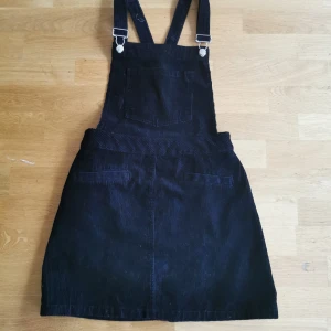 Hängsleklänning i svart manchester - Svart kort hängsleklänning i manchester. Stl 36 från Divided.  Fin modell och passform och bra skick. 