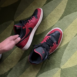 Jordan 1 reverse bread - Säljer ett par klassiska Nike Air Jordans i svart och rött. Skorna har en snygg design med svart snörning och den ikoniska Air Jordan-loggan på hälen. Perfekta för sneaker-entusiaster! Storlek 43 ny pris 2500