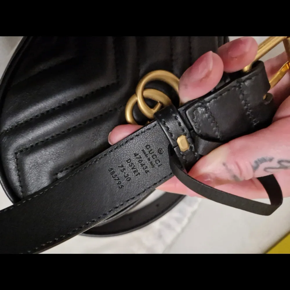 Snygg svart bältesväska från Gucci i quiltat skinn med det ikoniska GG-emblemet i guld. Väskan har en justerbar rem och en dragkedja för säker förvaring. Perfekt för att bära det viktigaste med stil.. Laukut & Käsilaukut.