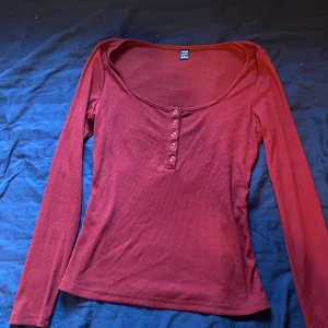 Röd ribbad topp - Snygg röd ribbad topp med långa ärmar och knappar framtill. Perfekt för en stilren look. Passar bra till både jeans och kjol.