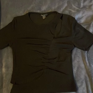 Svart topp  - Snygg svart topp  med korta ärmar och en unik rynkad detalj framtill.  Perfekt för en stilren look. Tillverkad i Turkiet 
