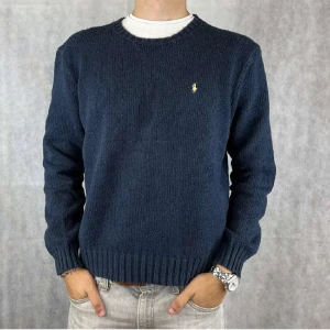 Mörkblå stickad Polo Ralph Lauren tröja  - Snygg mörkblå stickad tröja från Polo Ralph Lauren med ett gult polo Ralph lauren märkte vid bröstet. Tveka inte att höra av dig vid eventuella frågor!