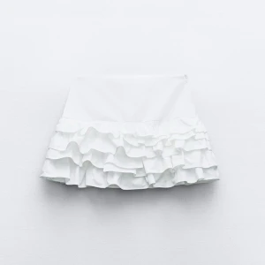 Vit kortkjol med volanger - Säljer en söt vit shortskjol med flera lager volanger. Perfekt till sommaren. Aldrig använd endast testad. Egna bilder vid intresse