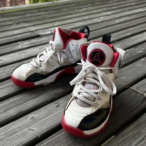 Jordans  - Snygga Jordans i vitt med röda och svarta detaljer. Skorna har en hög design med snörning och en ikonisk logga. Ganska slitna men fortfarande i bra skick, och kan fortfarande användas. 