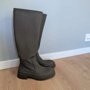 Höga gröna stövlar - Säljer ett par höga gröna stövlar med robust sula. Perfekta för regniga dagar och ger ett stilrent intryck. De är designade för att hålla fötterna torra och bekväma. Mossgröna och använt en gång 