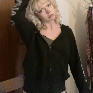 Svart hoodie med tryck - Säljer en svart hoodie med coolt motorcykelinspirerat tryck på ryggen och ärmarna. Hoodien har dragkedja framtill och en bekväm passform.