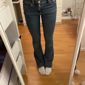 Blå jeans med bootcut - Snygga blå jeans med bootcut och middle waist. De har en klassisk femficksdesign och knappar framtill. Perfekta för en avslappnad stil.