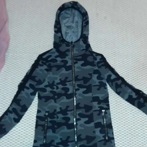 Camouflagejacka från Goldbergh - Snygg camouflagejacka från Goldbergh i storlek XS. Jackan har en huva och dragkedja framtill. Perfekt för en sportig look med sitt quick dry-material. Märkeslogga på ärmen ger en extra touch.