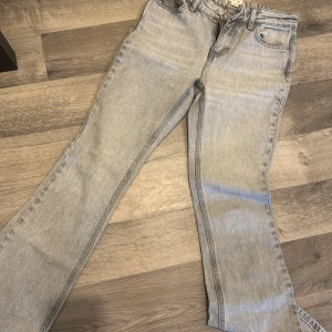 Grå jeans från Gina Tricot - Snygga grå jeans från Gina Tricot med en klassisk femficksdesign. De har en rak passform och är perfekta för en avslappnad stil. Jeansen har en knapp och dragkedja framtill.