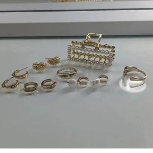 Guld- och pärlsmycken set - Elegant set med guld- och pärlsmycken. Inkluderar flera par örhängen och en hårklämma dekorerad med pärlor. Perfekt för att ge en lyxig touch till din stil.