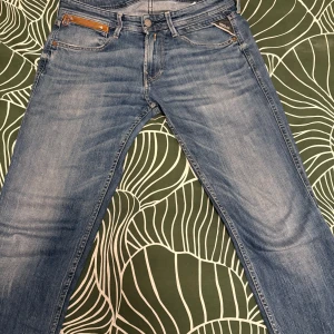 Blå jeans från Replay - Snygga blå jeans från Replay, modell Anbass. De har en klassisk femficksdesign med dragkedja och knapp. Perfekta för en avslappnad stil.