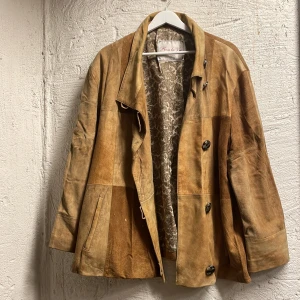 Beige mockajacka med mönstrat foder - Säljer en snygg beige mockajacka från Ross la Vie. Jackan har ett patchwork-mönster och knappar framtill. Insidan är fodrad, perfekt för höst och vår! En favorit men säljer på grund av platsbrist..