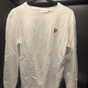 Vit långärmad tröja från Lyle & Scott - Säljer en stilren vit långärmad tröja från Lyle & Scott med deras ikoniska logga på bröstet. Perfekt för en avslappnad look. Tröjan är i bomull och har en klassisk passform. Passar bra till både jeans och chinos.