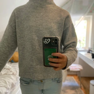 Grå stickad tröja från Kappahl - Mysig grå stickad tröja från Kappahl i storlek XS. Tröjan har en hög krage och långa ärmar med ribbade muddar. Perfekt för kyligare dagar. 💫